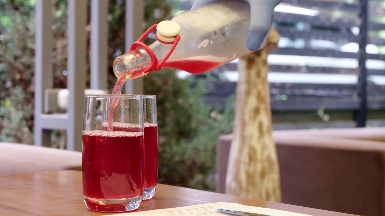 Waiter pouring red juice in glasses at a restaurant