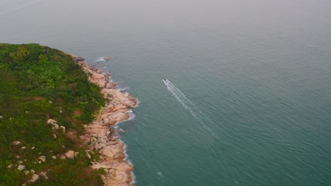 Drohnenschuss,-Der-An-Einem-Verschmutzten-Tag-über-Der-Küste-Einer-Insel-Auf-Ein-Boot-Zufährt,-Das-Sich-Davon-Entfernt