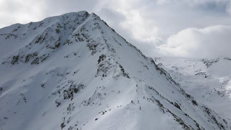 Panning-Slowmotion-panoramic-drone-shot-showing-skiers-and-snowboarders-riding-down-the-mountainside