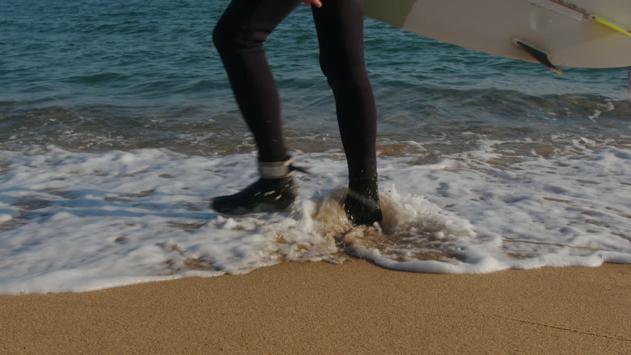 Surfer man walking to the beach at sunset preparing for surfing training and search for waves in Barcelona, spain, water, ocean exercise in sea with board, athletic male holiday or travel in vacation