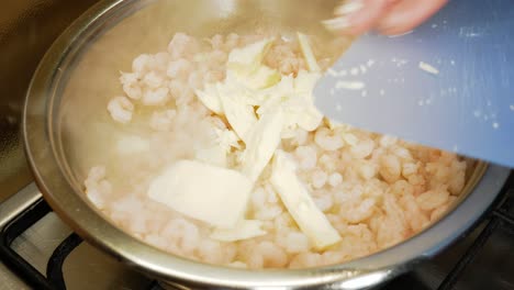 Pouring-fresh-butter-on-small-shrimps-cooking-in-steamy-pot