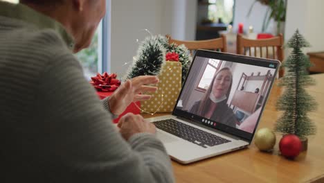 Feliz-Hombre-Mayor-Caucásico-En-Videollamada-Con-Una-Amiga-Con-Mascarilla-En-Navidad