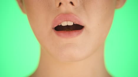 젊은 여자가 맛있는  ⁇  맛의 사탕을 혀에 녹이고 초록색 배경에 혀를  ⁇ 어내는 정적 클로즈업  ⁇