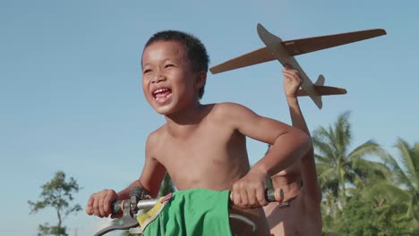 kids playing with cardboard airplane on a bike