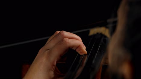 an extreme close-up of a musician playing the cello, on a seamless black studio background