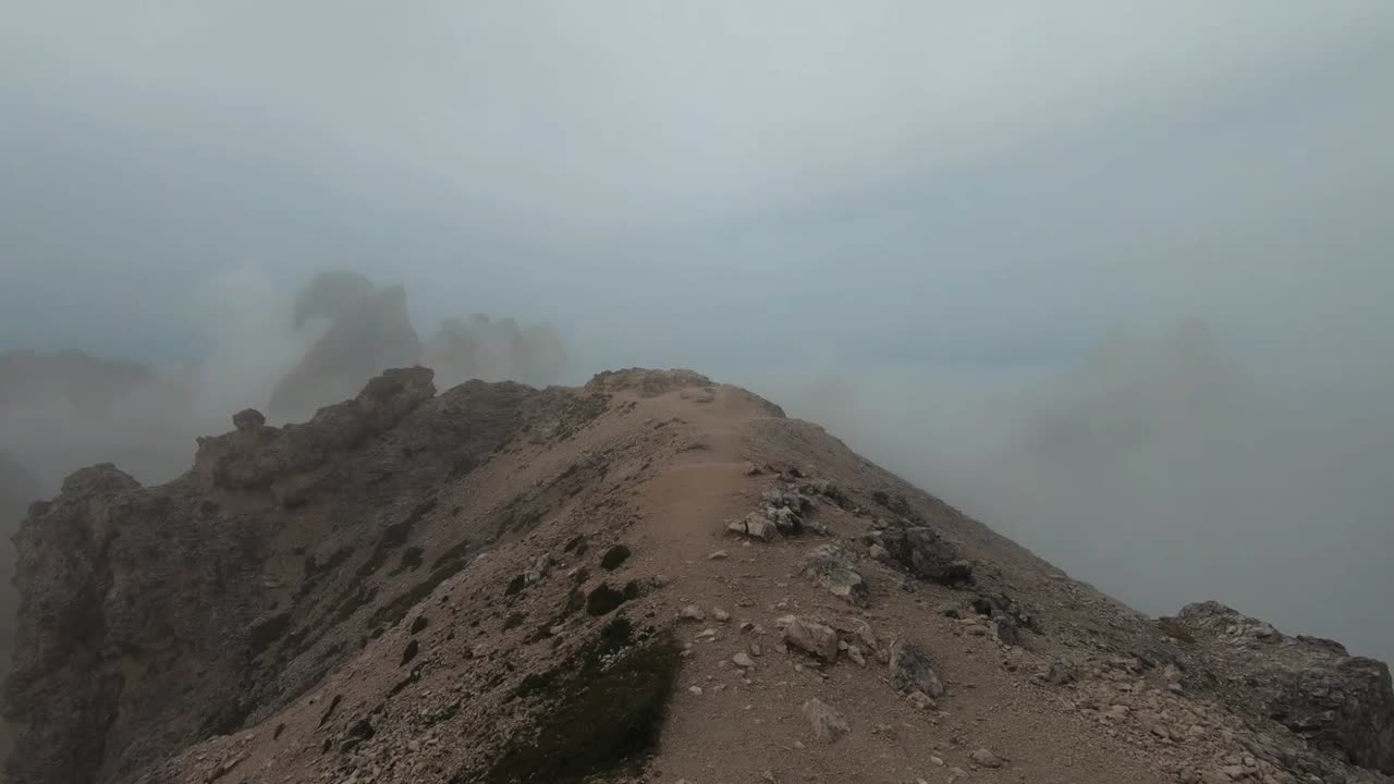 Fog lifting up and revealing the amazing Dolomite mountains.  Handhold camera movement.