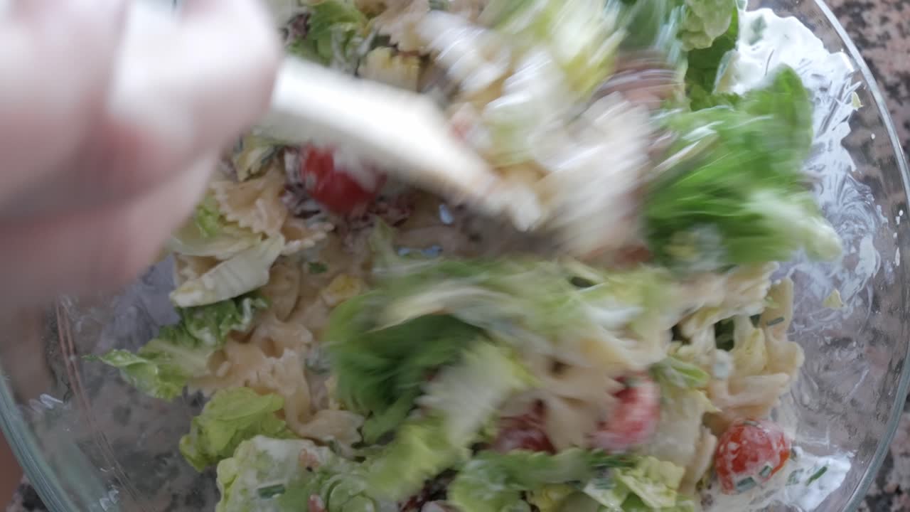 Freshly tossed pasta salad with lettuce, tomatoes, and creamy dressing in a bowl