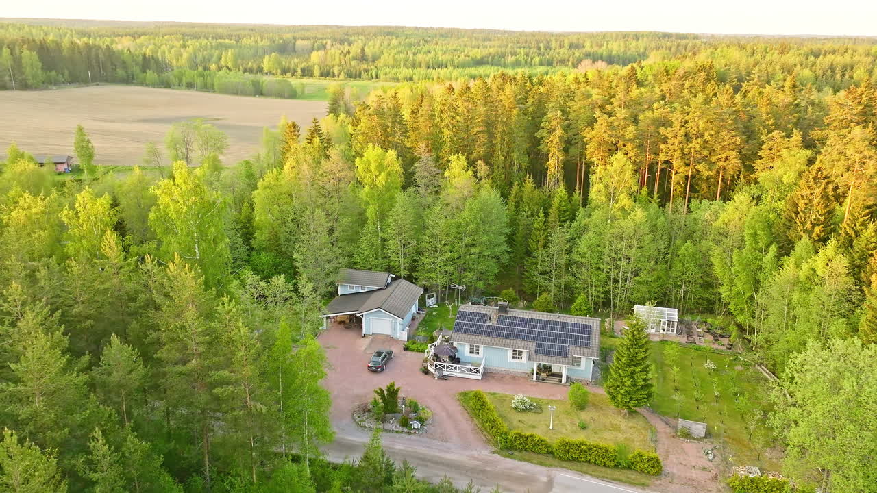 Selvforsynende hus midt i en solbeskinnet sommerskov i Norden - Luftfoto.
