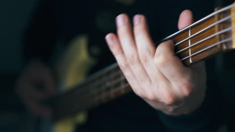 professional musician in black pullover plays bass guitar