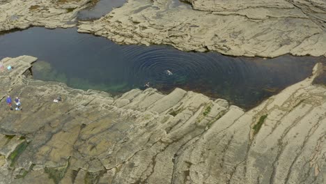 aerial view of people swimming in a natural rock pool