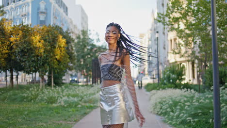 braids girl walking green alley. trendy brunette turning camera portrait