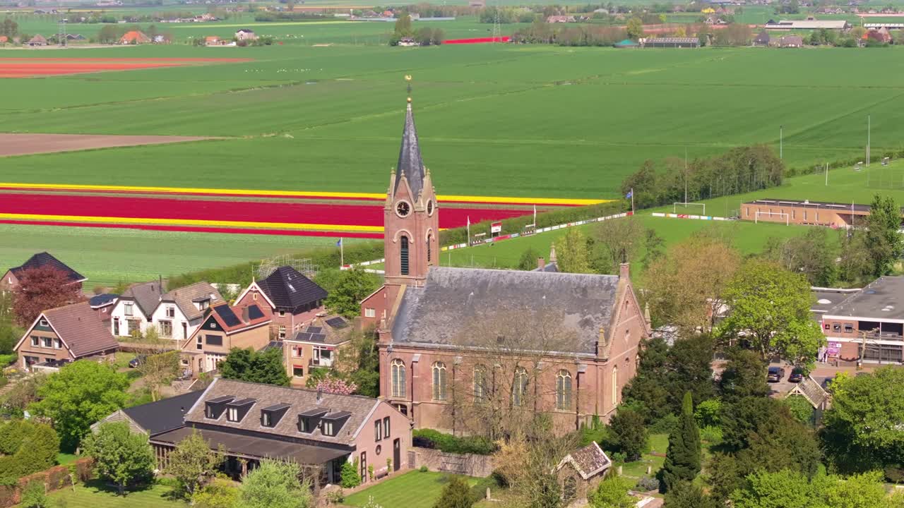 Vista aerea dei terreni agricoli di Berkhout costellati di tulipani e una chiesa storica.