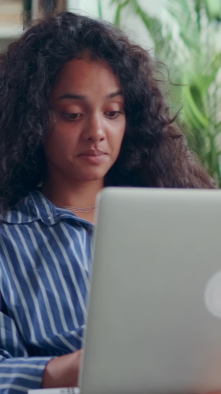 Young attractive focused indian woman student working with laptop