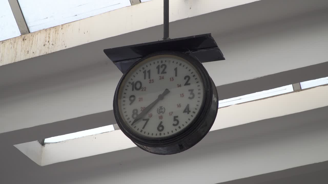 A close-up of a stopped clock at Poduyane train station in Sofia, Bulgaria. The setting is bright and simple with a clear view of the clock