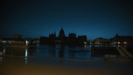 iconic hungarian parliament building across the flooded danube river with reflections of the city lights shimmering on the water