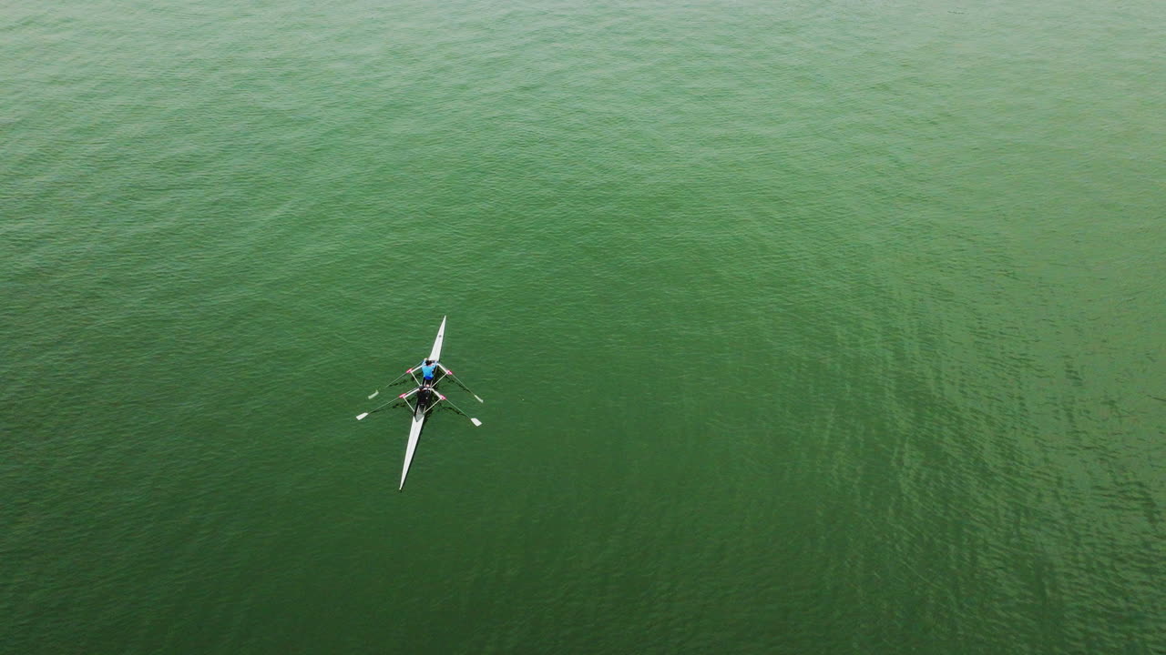 un dron giratorio disparó sobre dos personas en una canoa sobre un gran río en un día nublado