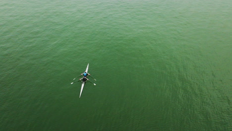 Rotating-drone-shot-over-two-people-in-a-canoe-over-a-large-river-on-a-cloudy-day