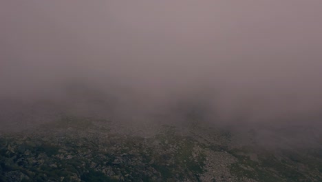 wide shot of aerial drone view of retezat mountains, romania seen through fog