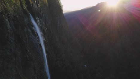 still view of ellenborough falls in australia with lens flare from the sun at golden hour, while water is falling off the cliff edge.