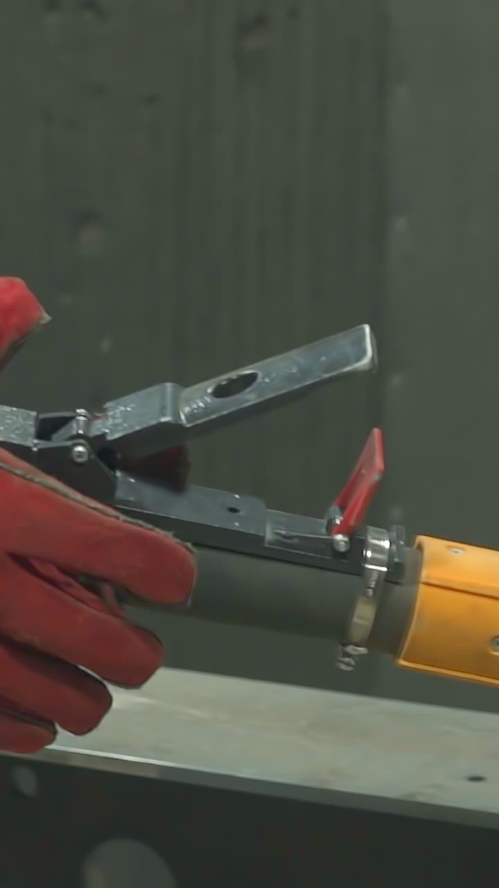 Employee in protective uniform and leather gloves holds powerful air brush in workshop closeup. Worker prepares equipment to paint materials at plant