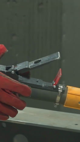employee in protective uniform and leather gloves holds powerful air brush in workshop closeup. worker prepares equipment to paint materials at plant