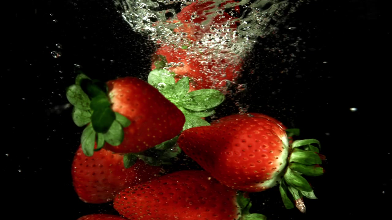 Fragole rosse fresche che schizzano nell'acqua al rallentatore
