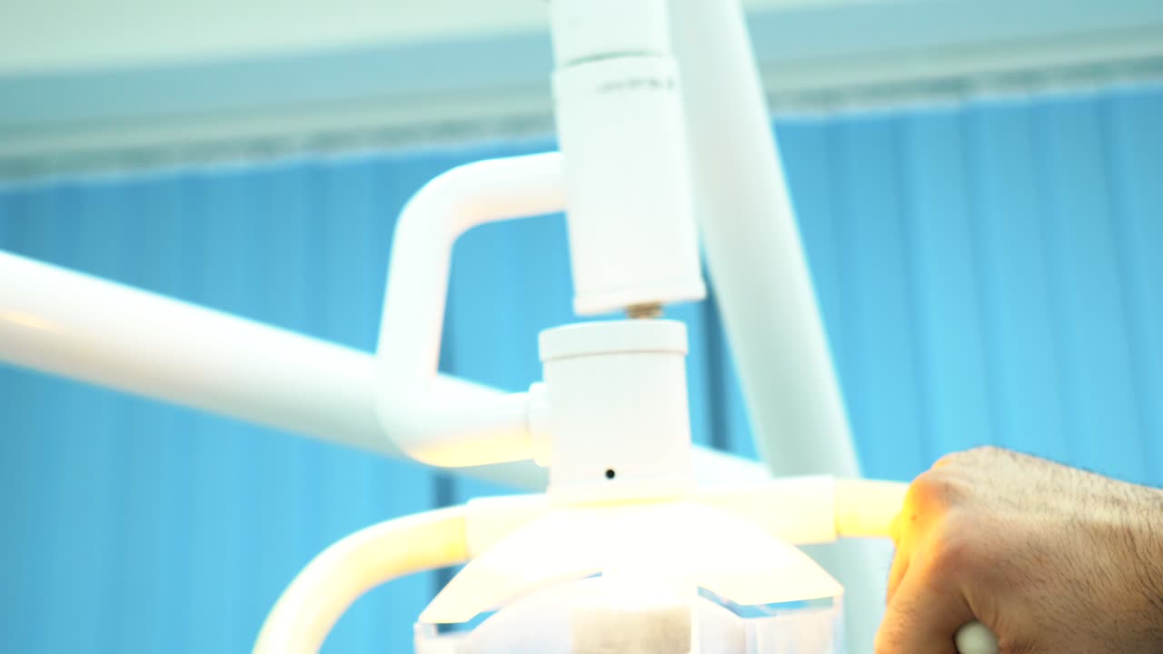 치과 의사가 치과 조명을 조정하고 있습니다.