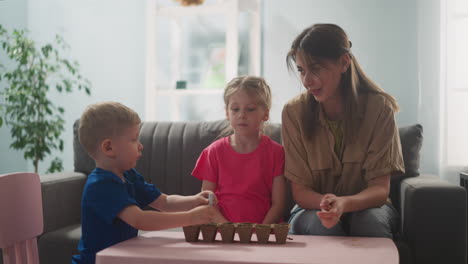 woman teaches children how to plant flowers, little child makes holes