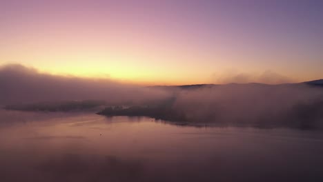 dawn at a lake with amazing colours, a mist floating over a water surface