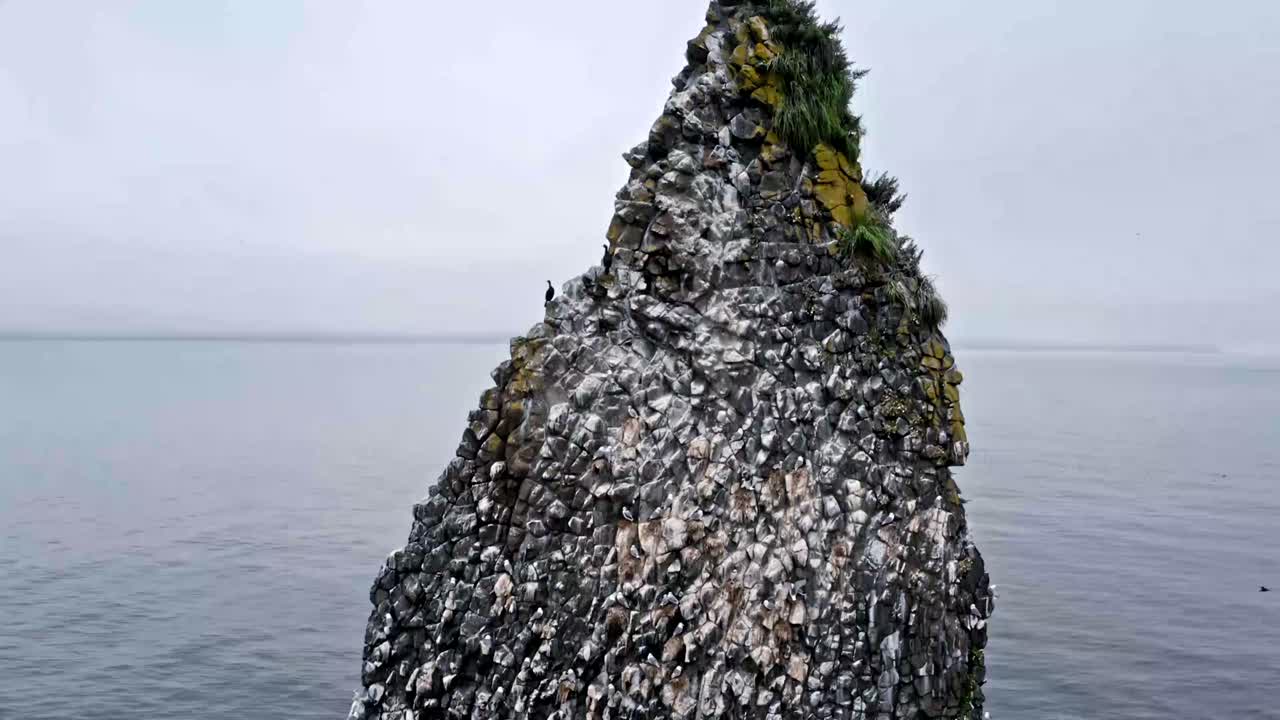 Stunning rock formation rises from calm ocean waters