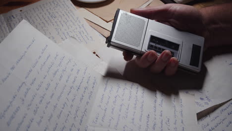 top view of a hand holding a tape recorder and a handwritten letter