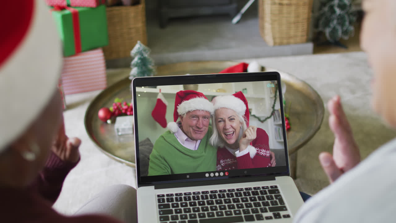 diversas amigas mayores que usan una computadora portátil para una videollamada de navidad con una pareja feliz en la pantalla