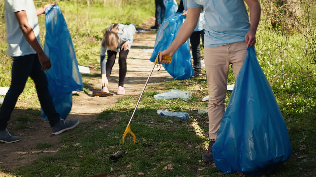 Young volunteer doing litter cleanup with a long claw to grab trash