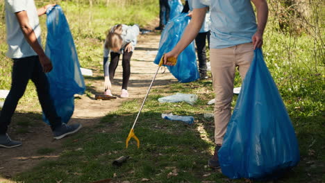joven voluntario haciendo limpieza de basura con una larga garra para agarrar la basura