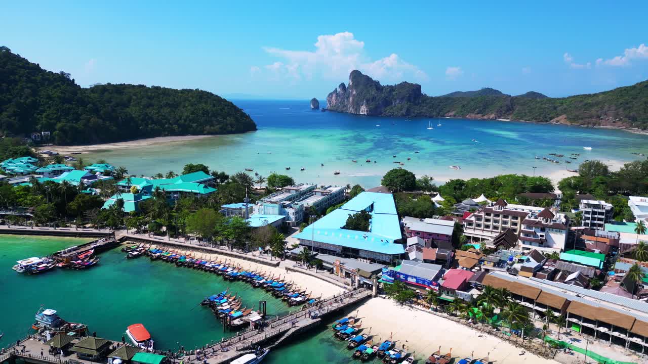 Barche ormeggiate al molo Tonsai dell'isola di Koh Phi Phi su acqua turchese in una giornata di sole in Thailandia. Splendida ripresa aerea con drone.