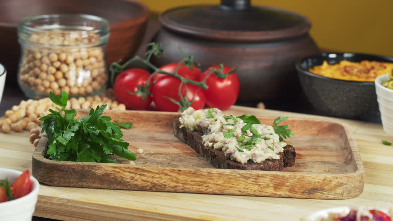 cocina israelí. manos tomando forshmak con pan de centeno negro decorado con perejil en primer plano. plato nacional de arenque judío, cultura de oriente medio. bocadillo tradicional vorschmack hecho de filete de pescado