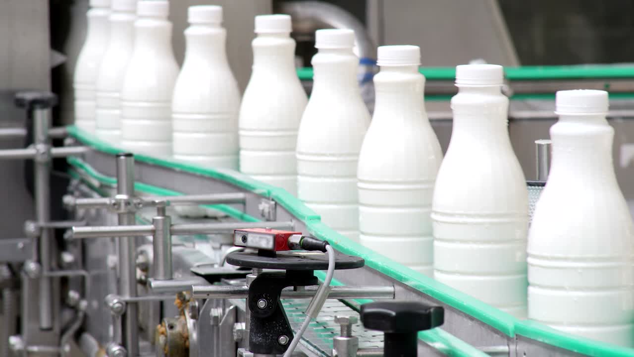 imágenes de botellas de leche de plástico blanco clasificadas en la línea de producción y que avanzan en una empresa lechera para ser procesadas