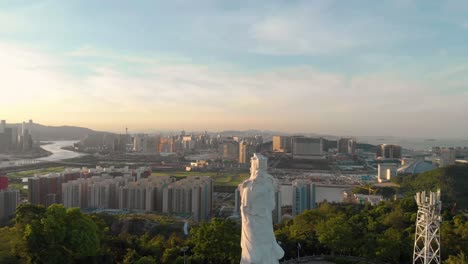 Rotating-aerial-view-of-Goddess-A-Ma-looking-over-Macau-cityscape-during-sunset