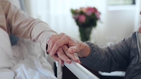 anciano, cama de hospital y mujer tomados de la mano