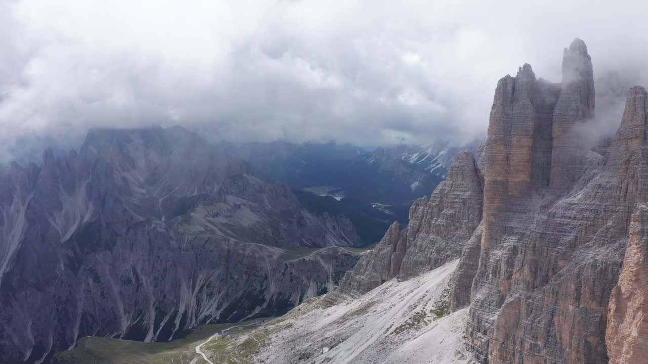 toma aérea de drones de nubes misteriosas que se ciernen alrededor de tre cime spires en los dolomitas