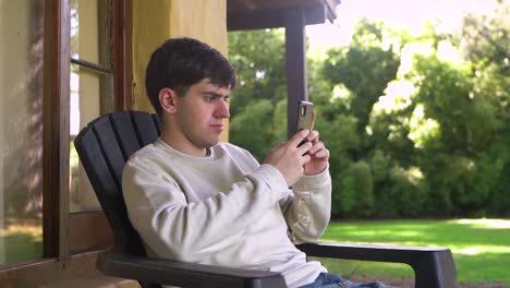 a young boy unwinding outdoors while engaged with a mobile phone - close up