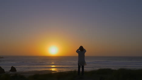 hombre en kaftan mira fijamente la impresionante puesta de sol sobre el horizonte del océano, amplio