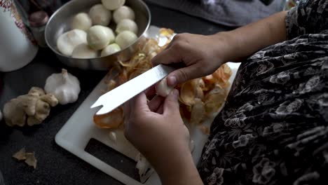 Vista-Sobre-El-Hombro-De-Manos-Pelando-Dientes-De-Ajo-Con-Cuchillo-De-Pan