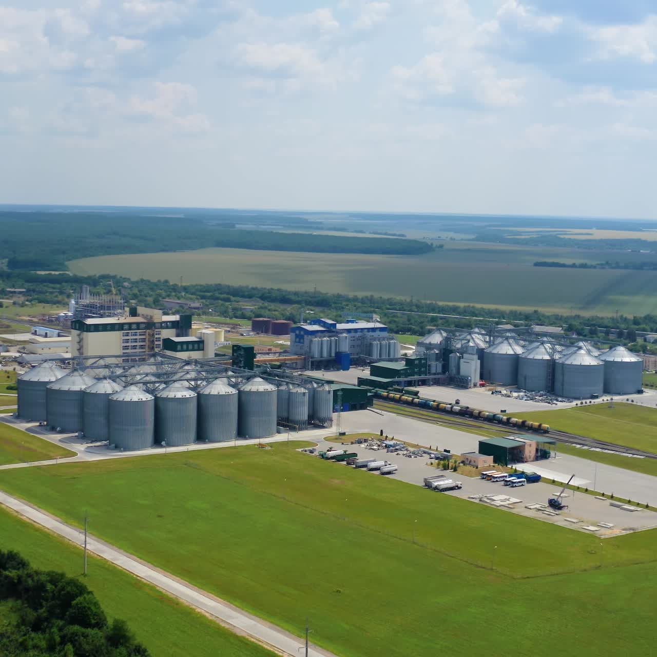 Grain elevators on beautiful landscape. Agricultural factory with granaries. Large aluminum containers for storing cereals. Aerial view