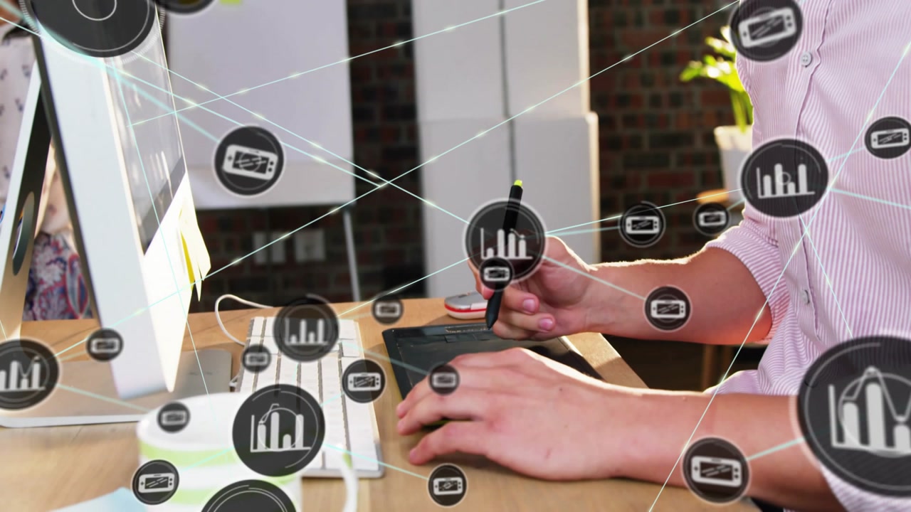 Man at desk facing monitor emitting data icons passing across frame, typing and analyzing data
