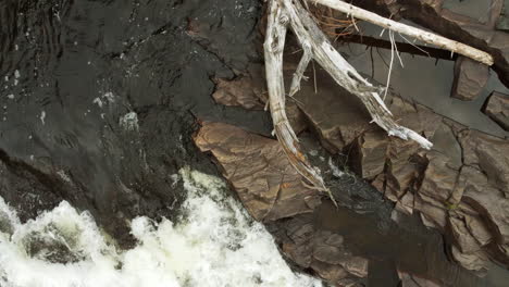 Wasserfall,-Der-Am-Flussufer-Schäumt,-Luftdrohne-Herauszoomen