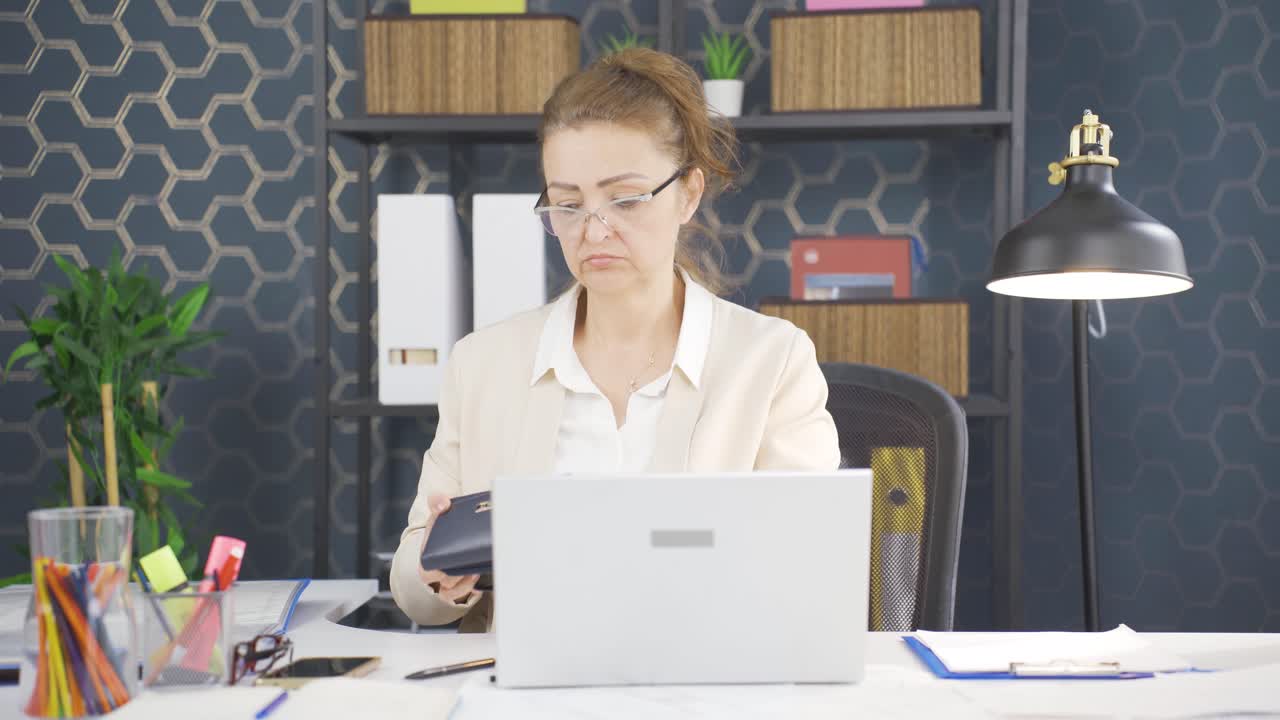 una donna d'affari che mostra il suo portafoglio vuoto alla telecamera.