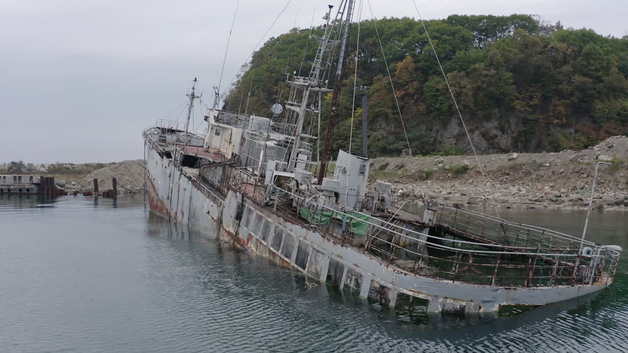 흐린 흐린 날 해안 근처에 정박한 녹슨 회색 반 침수 난파선