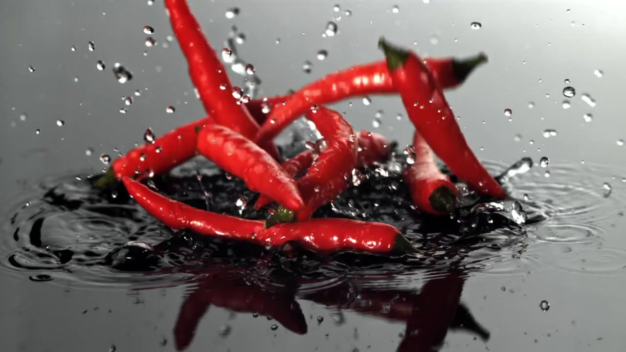 Red Chili Peppers Falling and Splashing into Water in Slow Motion