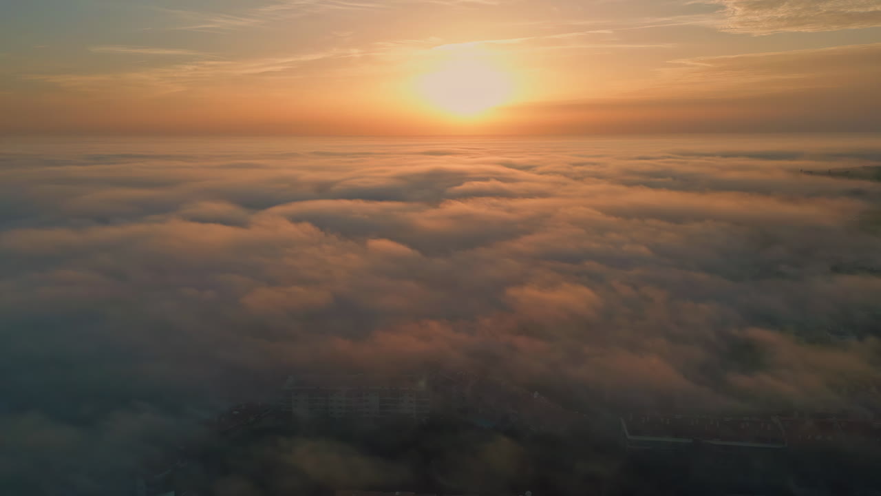 Golden sun setting down over clouds covering nature. Aerial view bright sunset